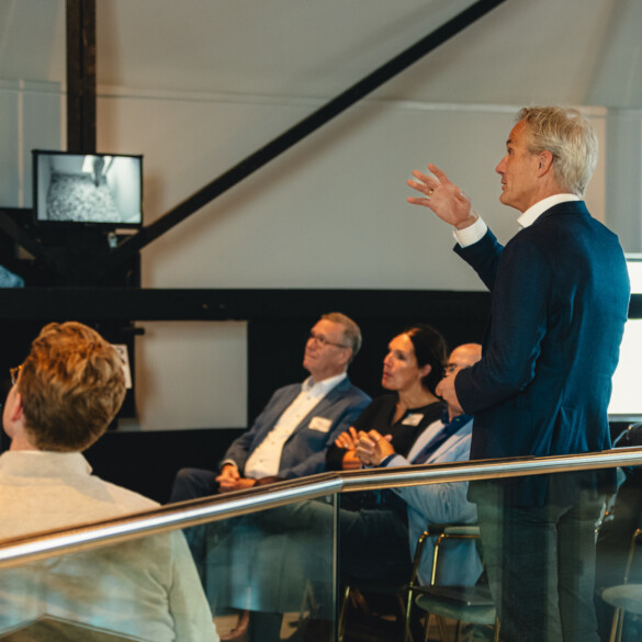 Frans Hamstra van @north staat in een vergaderzaal en geeft een presentatie aan een zittend publiek.