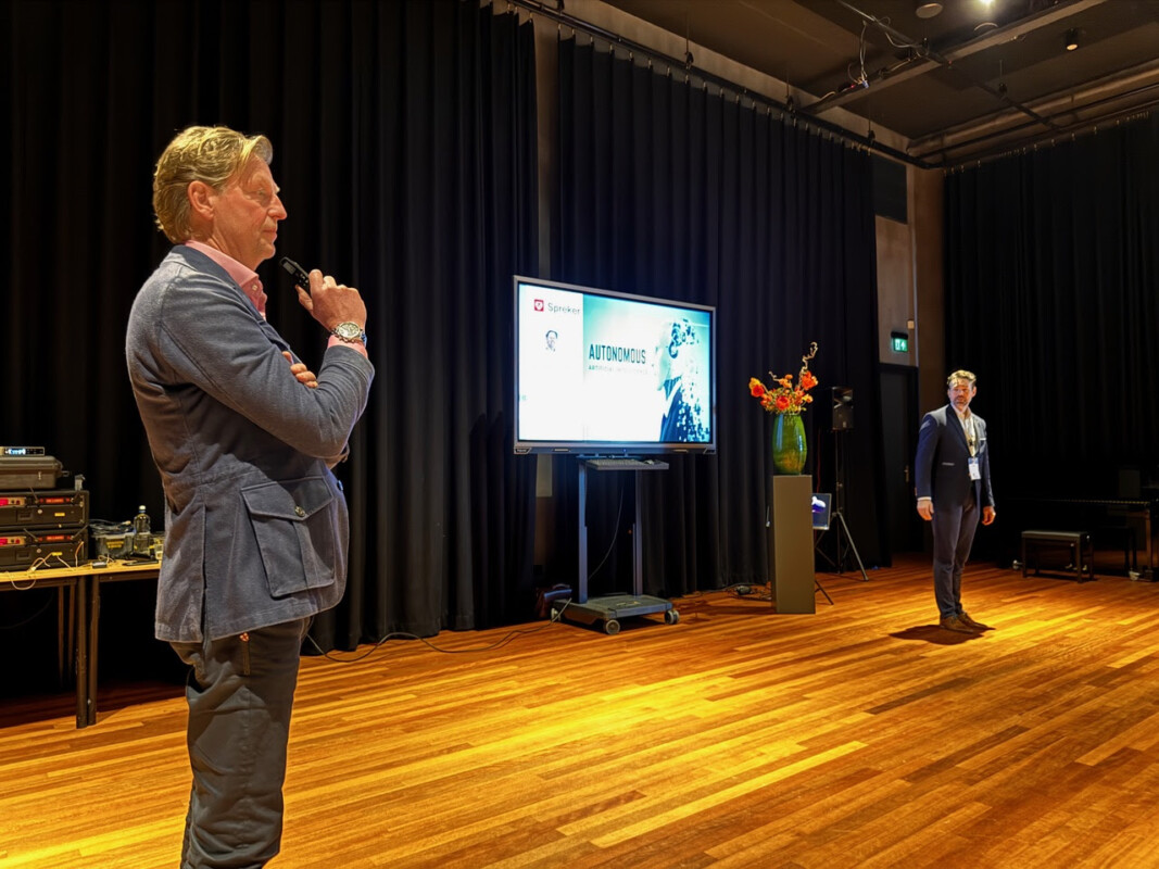 Evert-Jeen van der Meer van AON staat in een congreszaal en geeft een lezing over aansprakelijkheid en veiligheid van autonome voertuigen.