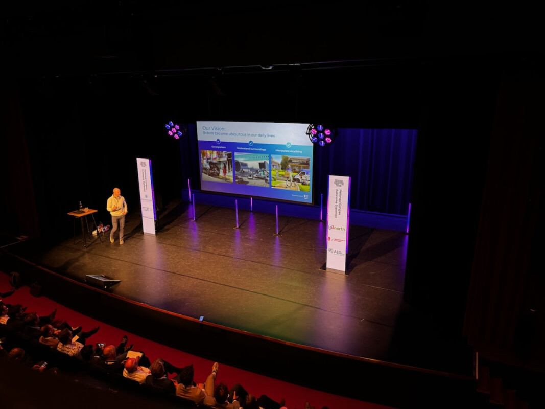 Keynote speaker Aaron Saunders van Boston Dynamics staat op het podium tijdens congres.